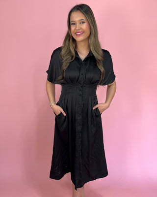 Woman wearing a black dress against a pink background