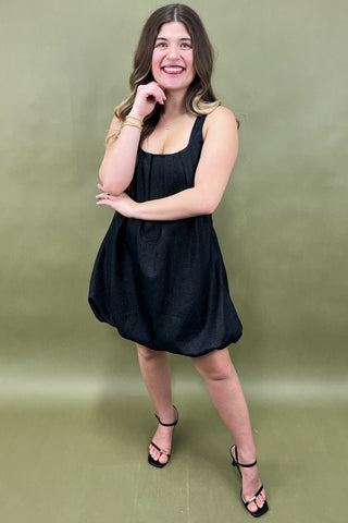 Woman wearing a black dress against a green background