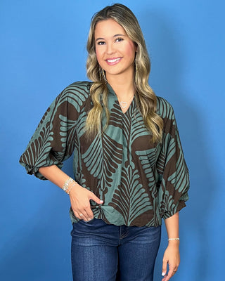 Sage green and brown leaf print blouse with a V-neckline, relaxed fit, and three-quarter balloon sleeves.