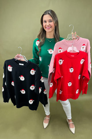 Woman holding four sweaters with Santa face patterns on a green background