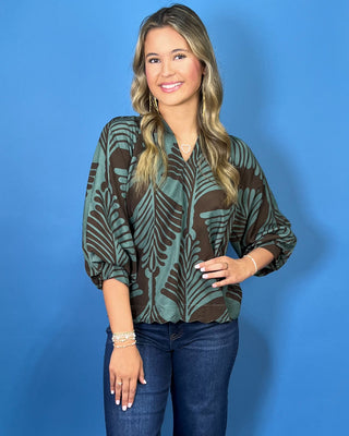 Sage green and brown leaf print blouse with a V-neckline, relaxed fit, and three-quarter balloon sleeves.