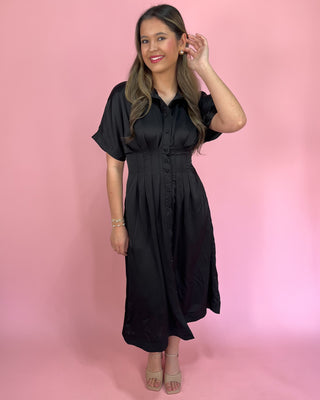 Woman wearing a black dress against a pink background
