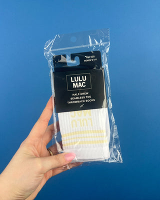 Lulu Mac Half-Crew Seamless Toe Single Pair Socks. In colors Hot Pink, Light blue, Orange, Grey, and Tan. Displayed against a solid blue background. 