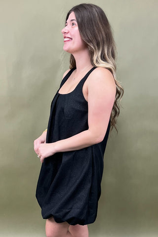 Woman wearing a black sleeveless dress against a green background
