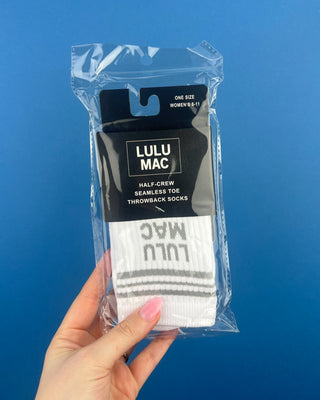 Lulu Mac Half-Crew Seamless Toe Single Pair Socks. In colors Hot Pink, Light blue, Orange, Grey, and Tan. Displayed against a solid blue background. 