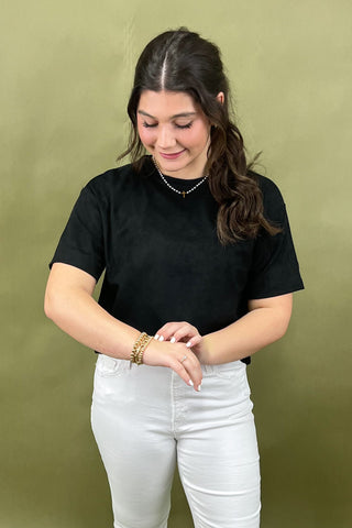 Woman wearing a black t-shirt and white pants against a green background