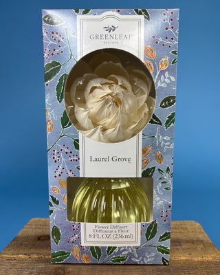 Greenleaf Laurel Grove flower diffuser in its original patterned packaging, featuring a cream-colored flower reed and a green glass bottle, set against a blue background.
