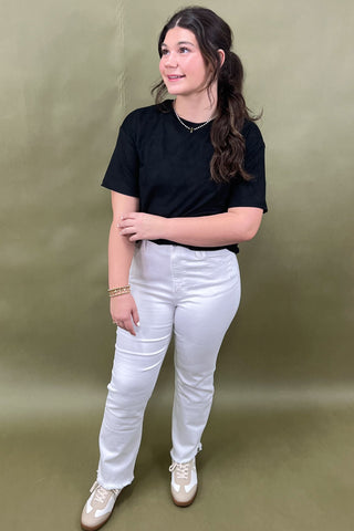Person wearing a black t-shirt and white pants against a green background