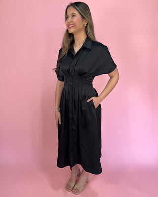 Woman wearing a black dress against a pink background