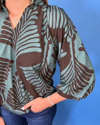 Sage green and brown leaf print blouse with a V-neckline, relaxed fit, and three-quarter balloon sleeves.
