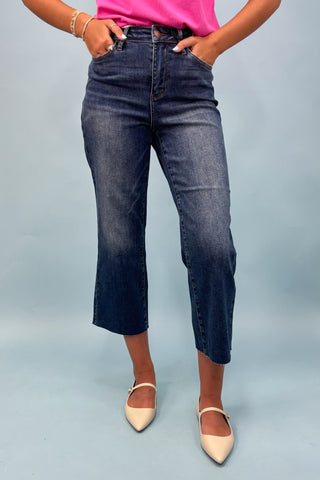 Person wearing blue jeans and pink top on a light gray background