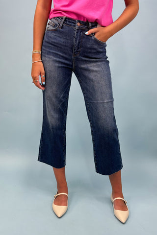 Person wearing blue jeans and a pink top on a gray background