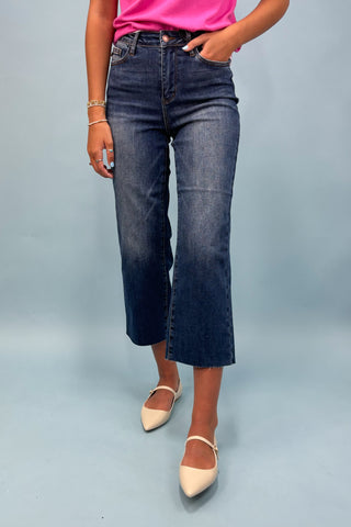 Person wearing blue jeans and a pink top on a gray background