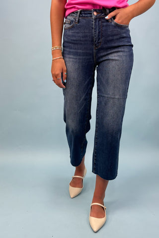 Person wearing dark blue jeans and a pink top on a light gray background