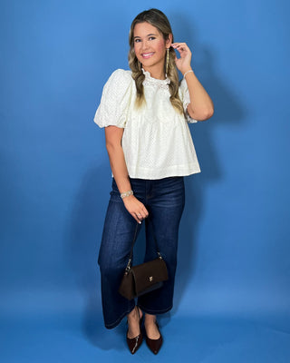 Ivory eyelet blouse with lace detailing, a ruffle neckline, and statement puff sleeves.