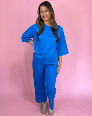 Woman wearing a blue outfit against a pink background