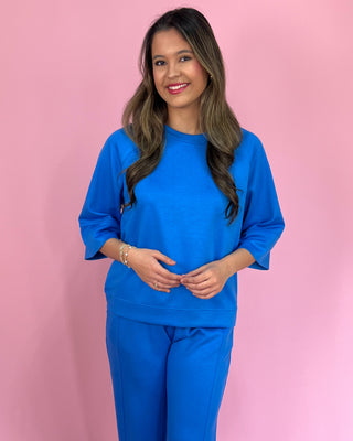 Woman wearing a blue outfit against a pink background