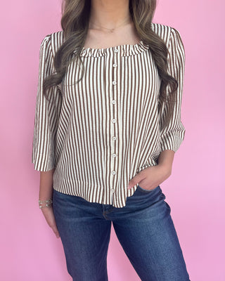 Person wearing a striped blouse and jeans against a pink background