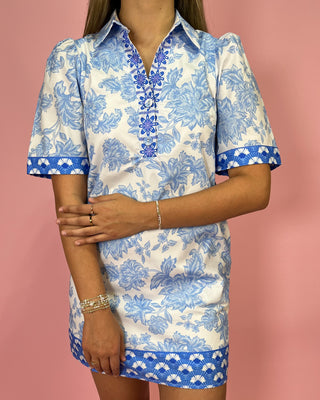 Woman wearing a blue and white floral dress against a pink background