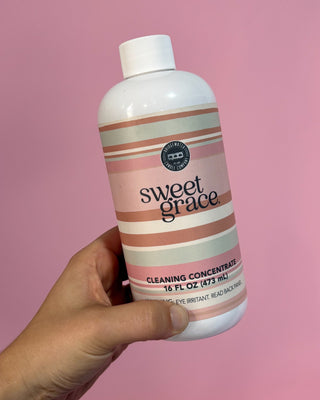 Bridgewater Candle Company Sweet Grace Multi-Surface Cleaning Concentrate in a 16 oz bottle with a pink striped label, designed to clean sealed wood, stone, tile, laminate, vinyl, countertops, and other non-porous household surfaces while leaving the signature Sweet Grace fragrance.