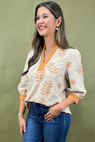 Woman wearing a floral blouse with orange accents against a green background