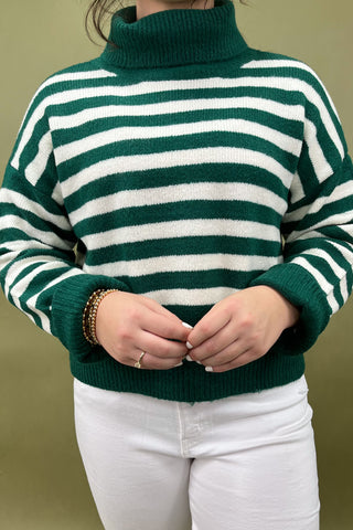 Green and white striped sweater worn by a person on a green background
