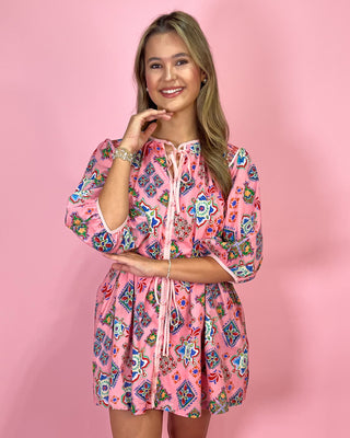 Woman wearing a pink floral dress against a pink background
