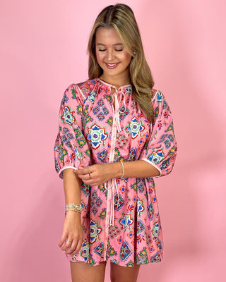 Woman wearing a pink floral dress against a pink background