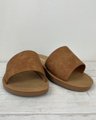 Pair of brown sandals on a light wooden floor.