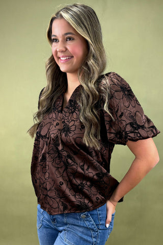 Woman wearing a brown floral blouse against a green background