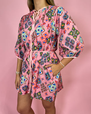 Person wearing a colorful patterned dress on a pink background