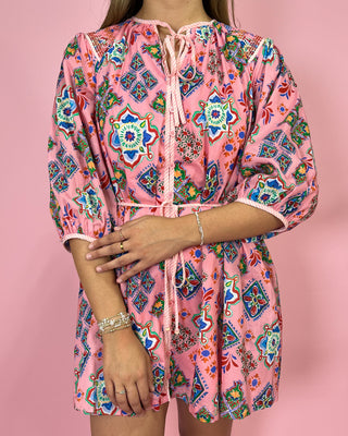 Person wearing a pink dress with colorful patterns on a pink background