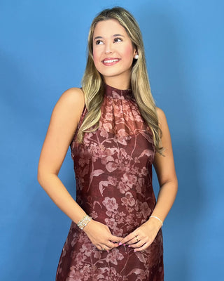 A woman with blonde hair wearing a sleeveless, high-neck, dark brown floral lace dress