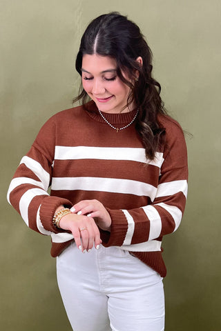 Woman wearing a brown and white striped sweater against a green background
