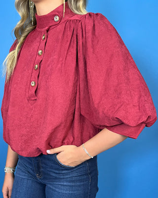 Burgundy stand collar blouse with button-front detail, three-quarter puff sleeves, and a relaxed fit.
