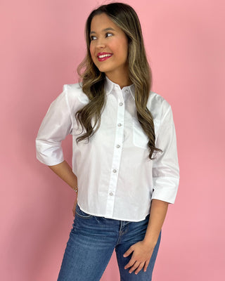 Woman wearing a white shirt and blue jeans against a pink background