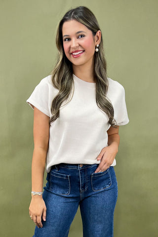 Woman wearing a white blouse and blue jeans against a green background