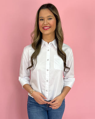 Woman wearing a white shirt and blue jeans against a pink background