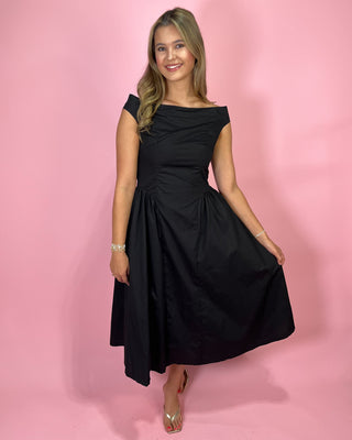 Woman wearing a black dress against a pink background