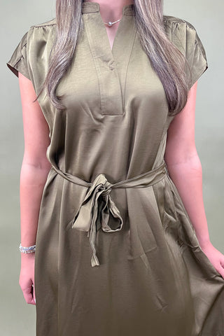 Woman wearing a beige dress against a plain background