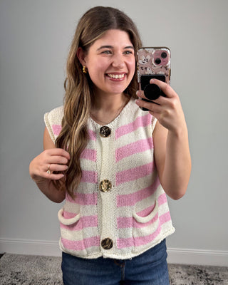 Woman taking a selfie wearing a pink and white striped vest with buttons.