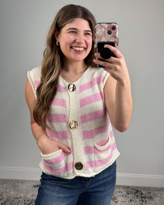 Woman taking a selfie wearing a pink and white striped cardigan with buttons.