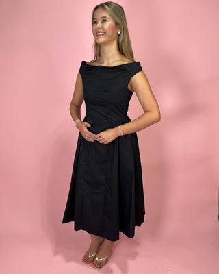 Woman wearing a black dress against a pink background