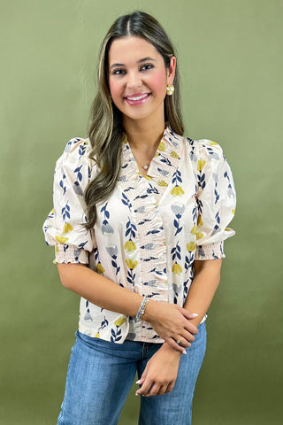 Woman wearing a floral blouse and jeans against a green background