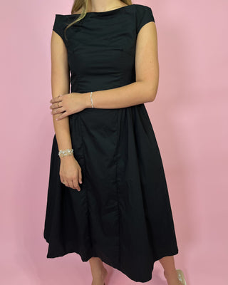 Woman wearing a black dress against a pink background