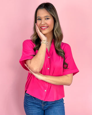 Woman wearing a pink shirt and blue jeans against a pink background