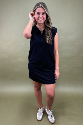 Woman wearing a black sleeveless dress with a green background