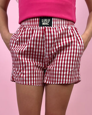 Red and white checkered shorts with a visible brand label on a pink background