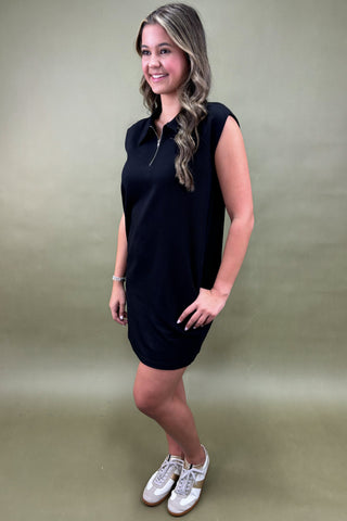 Woman wearing a black dress against a plain background