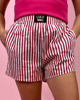 Red and white striped shorts with a visible brand label on a pink background